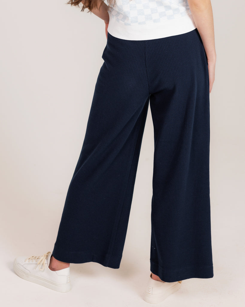 Model wearing a dark blue, flared, cropped, sweatpant.