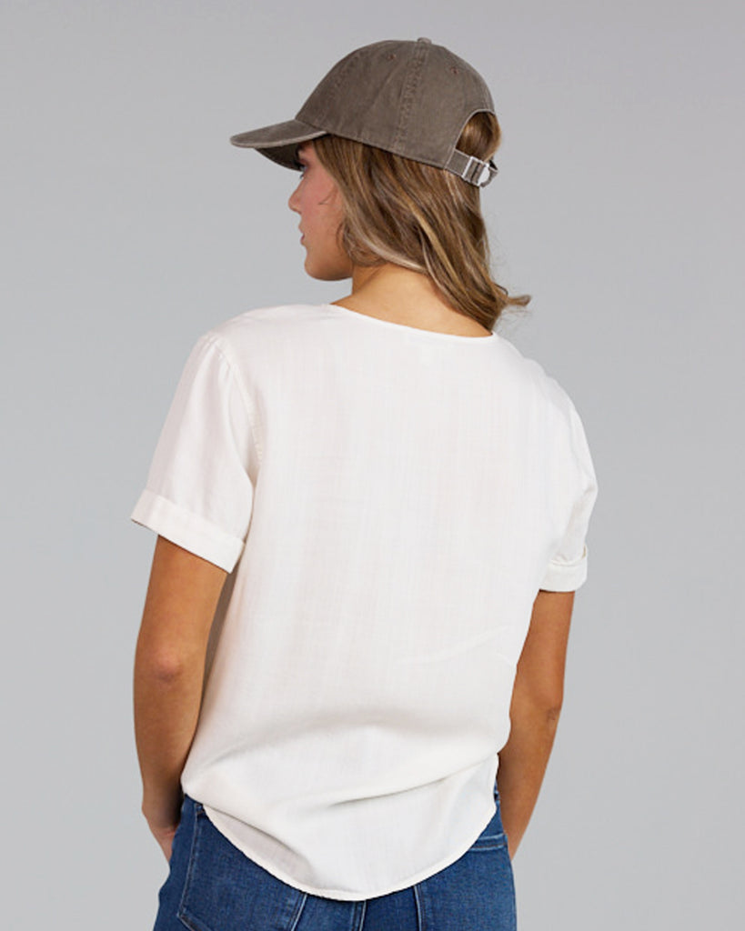 Model wearing a white short sleeve with cuff, round neck loose fitting blouse.