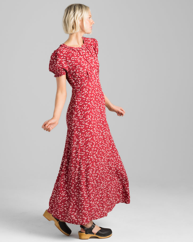 Model wearing a red with white floral print, short sleeve, round neck with ruffle details, maxi length slip dress.