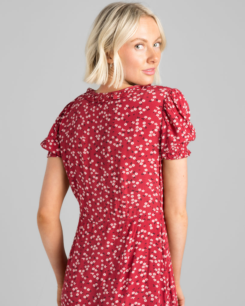 Model wearing a red with white floral print, short sleeve, round neck with ruffle details, maxi length slip dress.