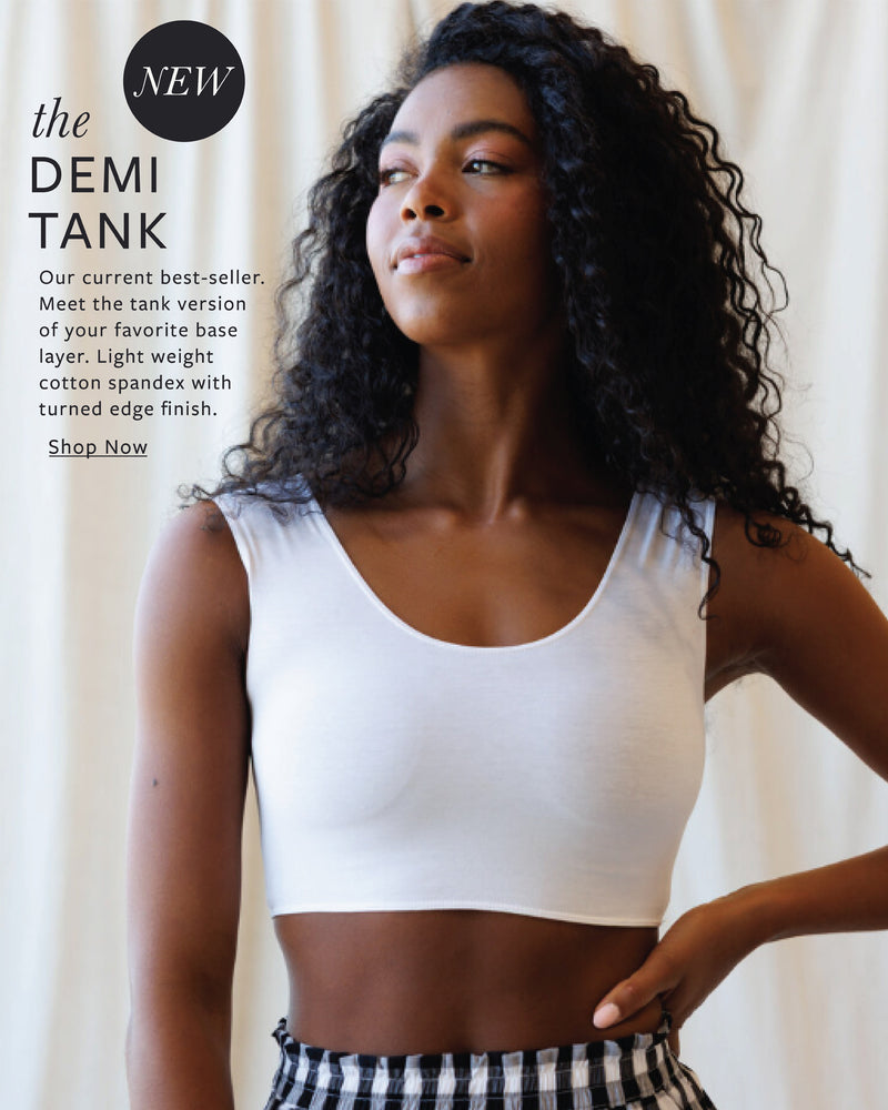 Woman wearing a white demi tank top with text about the product on a plain background