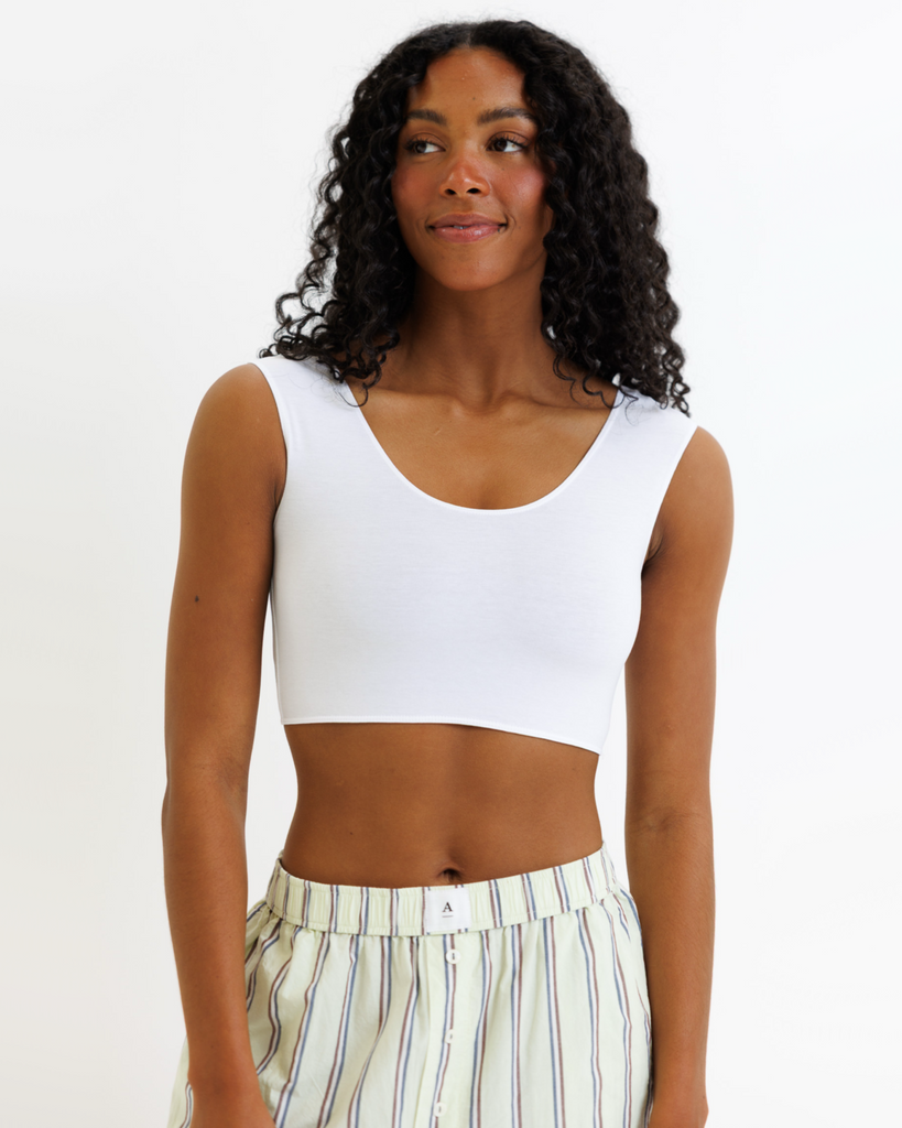 Woman wearing a white cropped tank top and striped pants on a white background