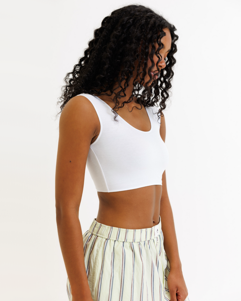 Woman wearing a white cropped tank top and striped pants on a white background