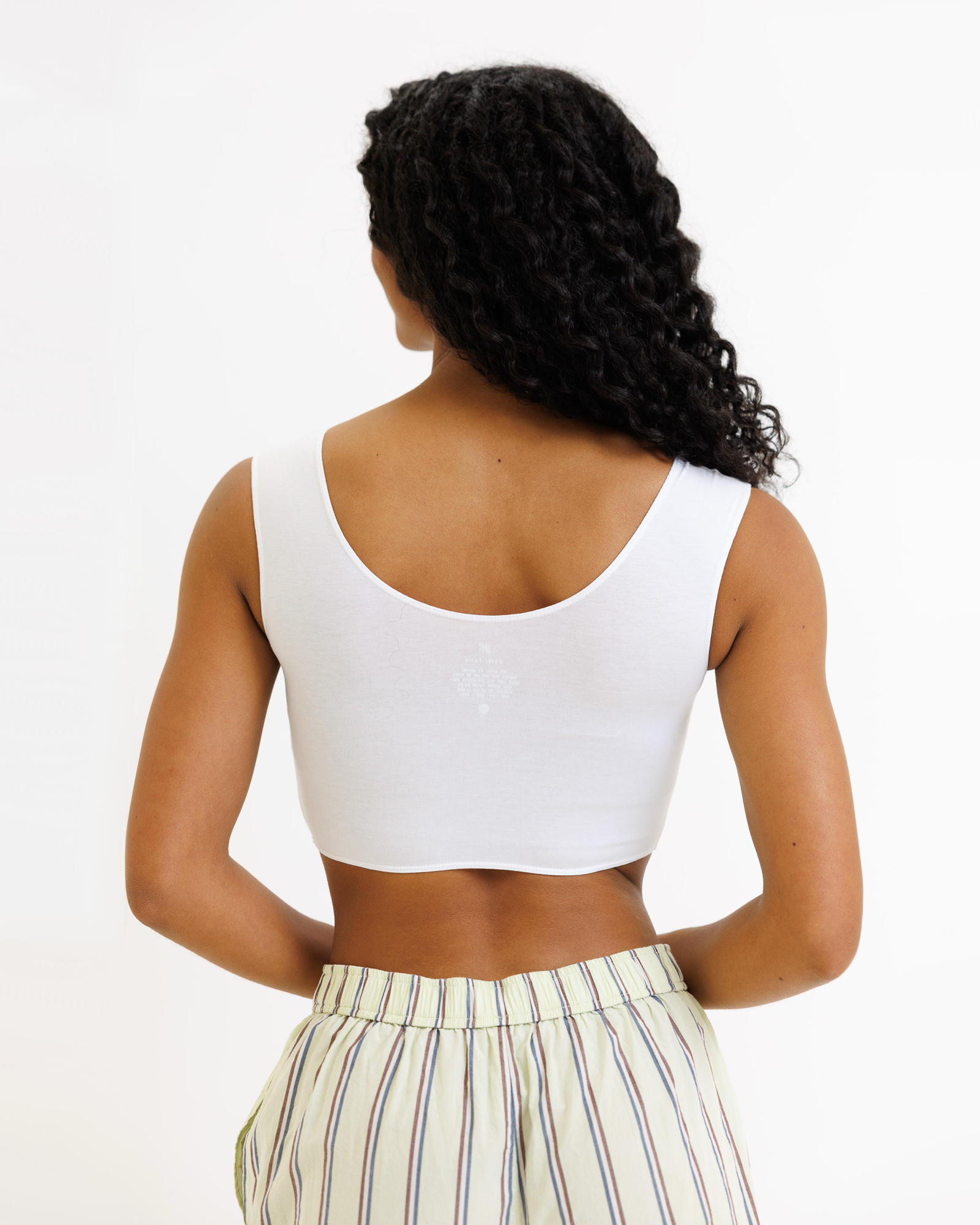 Woman wearing a white cropped tank top and striped pants on a white background