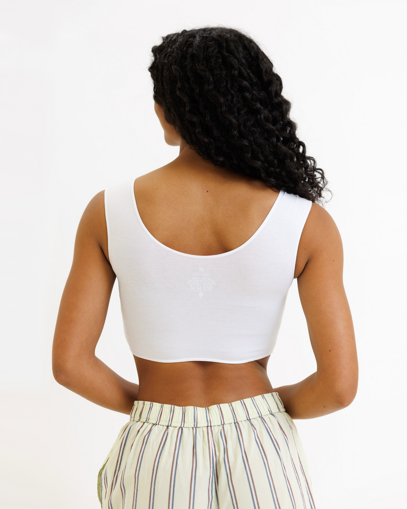Woman wearing a white cropped tank top and striped pants on a white background
