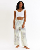 Woman wearing a white cropped tank top and striped pants on a white background