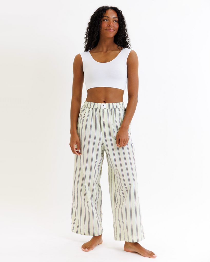 Woman wearing a white cropped tank top and striped pants on a white background