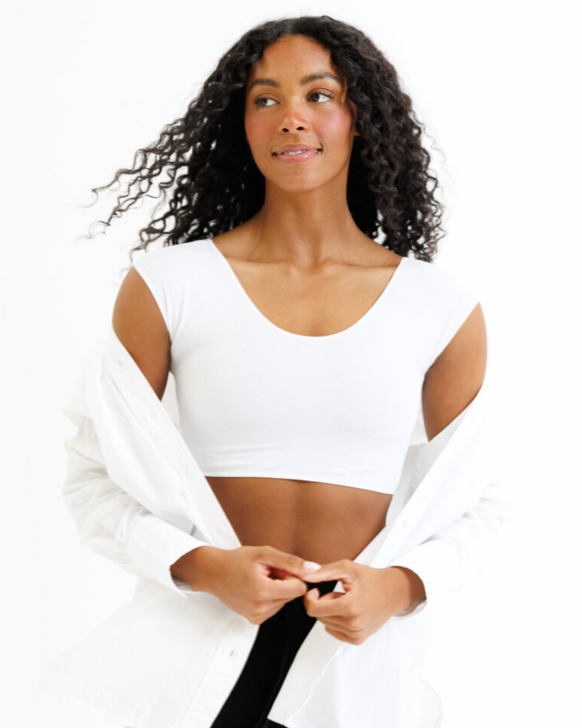 Woman wearing a white cropped layering top and white button-down on a white background
