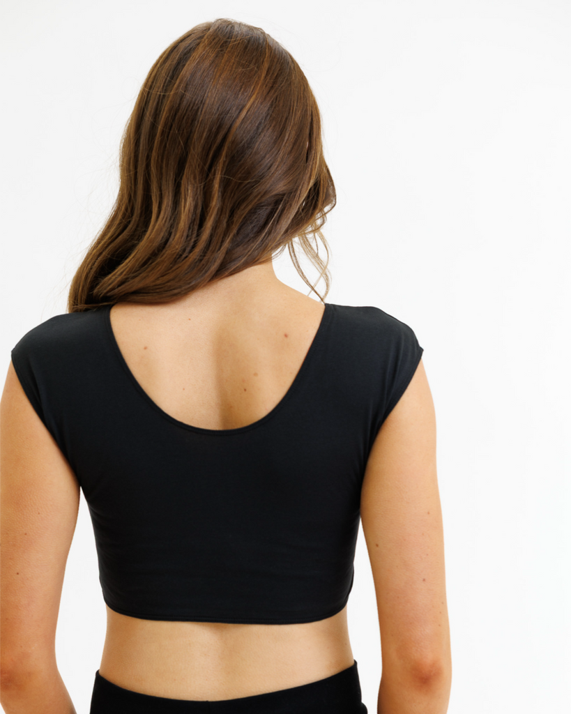 Woman wearing a black cropped layering top on a white background