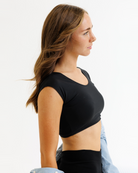Woman wearing a black cropped layering top on a white background