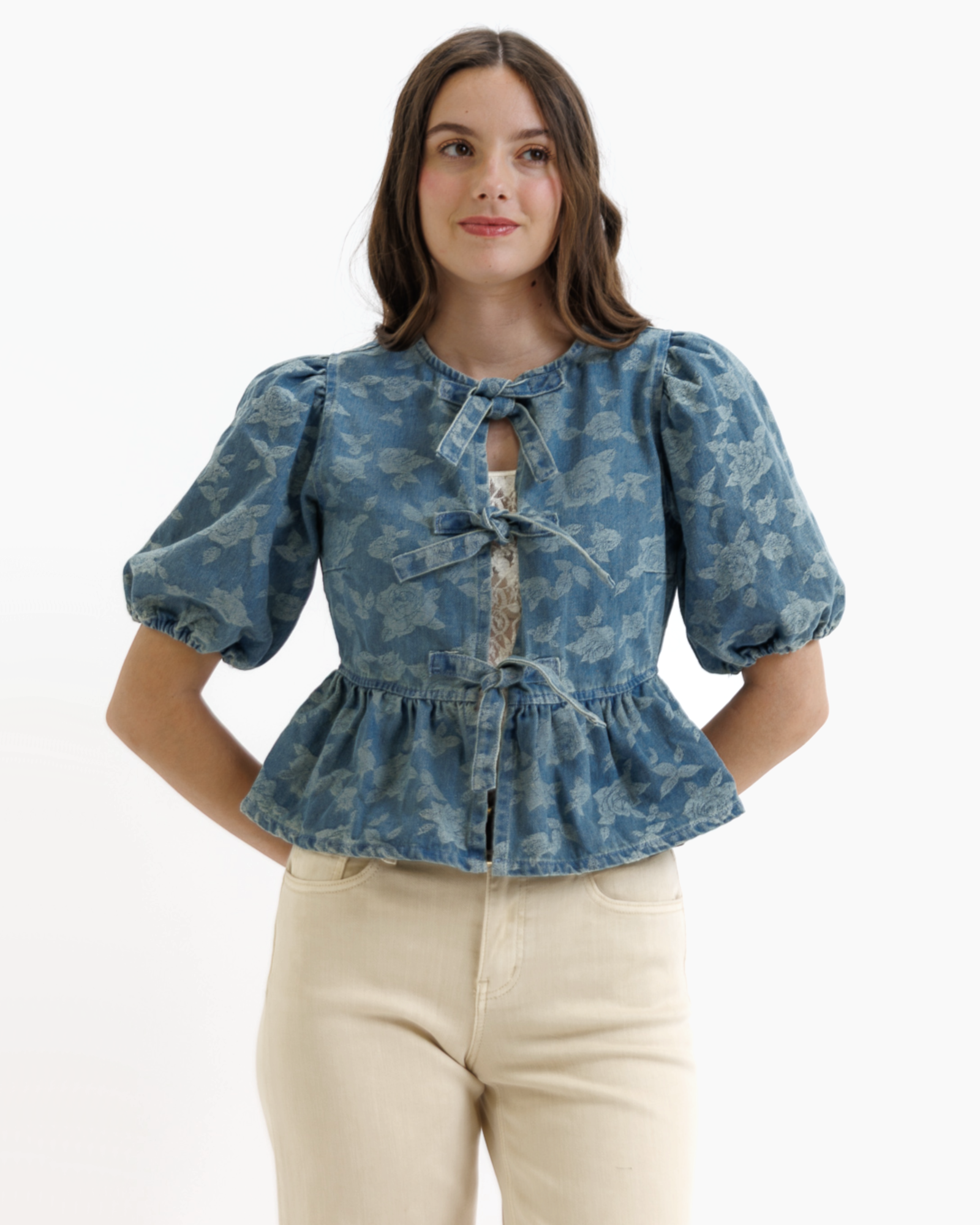 Woman wearing a blue denim floral blouse with puffed sleeves on a white background