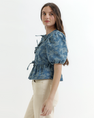 Woman wearing a blue denim floral blouse with puffed sleeves on a white background