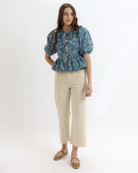 Woman wearing a blue denim floral blouse with puffed sleeves on a white background