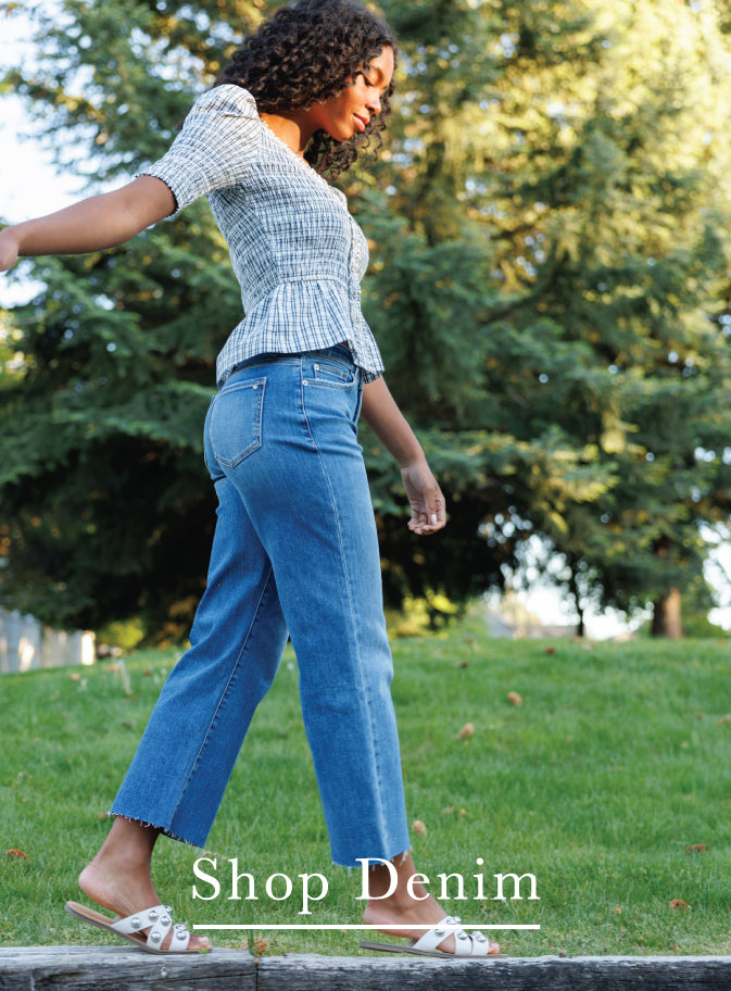 A woman walking outdoors on a grassy lawn wearing a blue cropped denim top and matching blue jeans, with the text 'Shop Denim' overlaid at the bottom.
