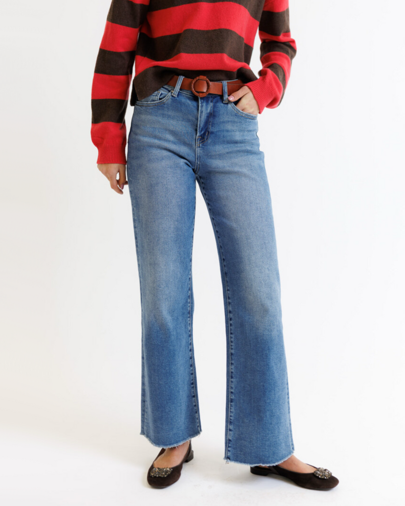 Woman wearing a red and brown striped sweater with blue jeans on a white background