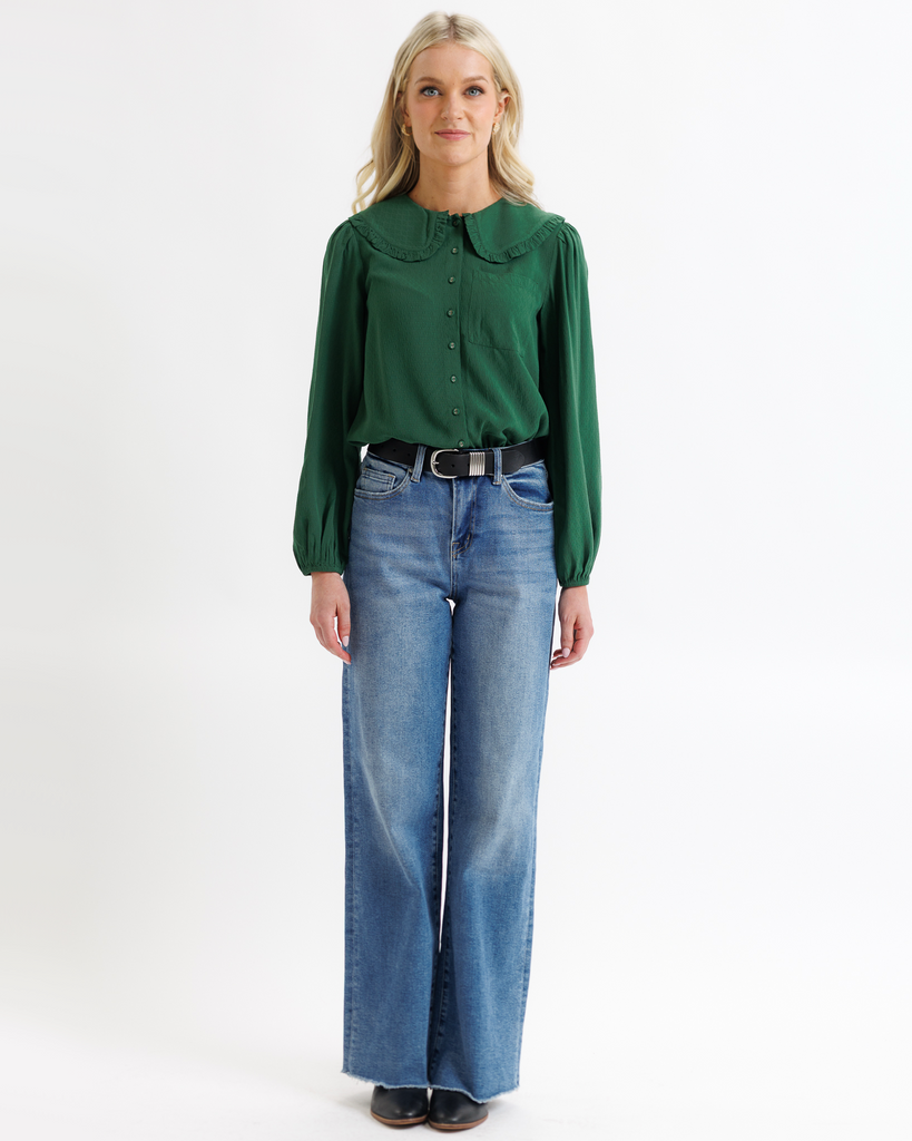 Woman wearing a green blouse and blue jeans on a white background