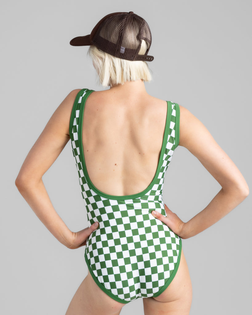 Model wearing a green and white checkered one-piece swimsuit with a low-cut back.