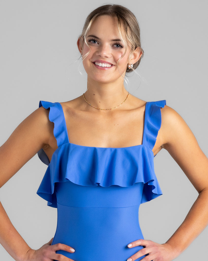 Model wearing a blue square neck one-piece swimsuit with ruffles on the sleeves and across the chest.