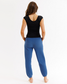 Woman wearing a black top with blue knit pants on a white background