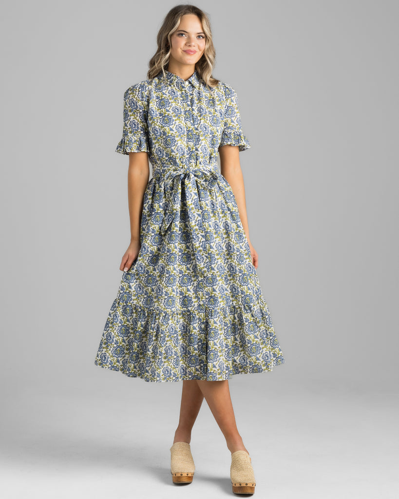 Model wearing a blue and green floral print, short sleeve with ruffles, buttondown, collared, midi length dress.