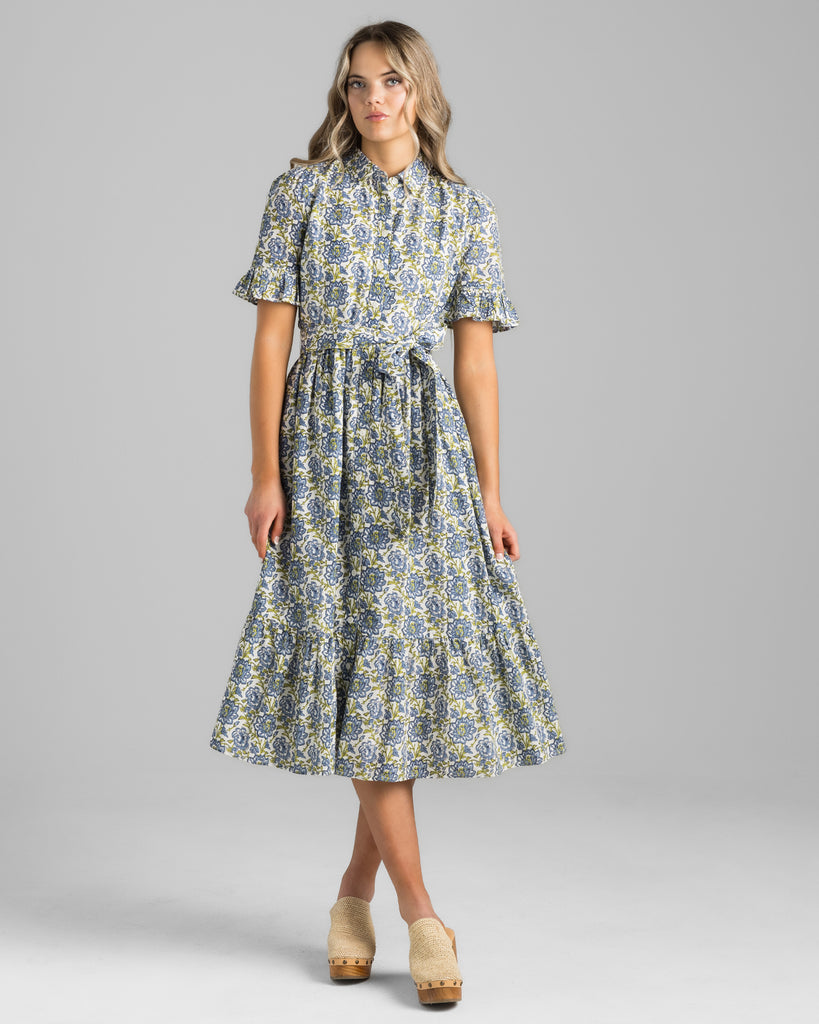 Model wearing a blue and green floral print, short sleeve with ruffles, buttondown, collared, midi length dress.