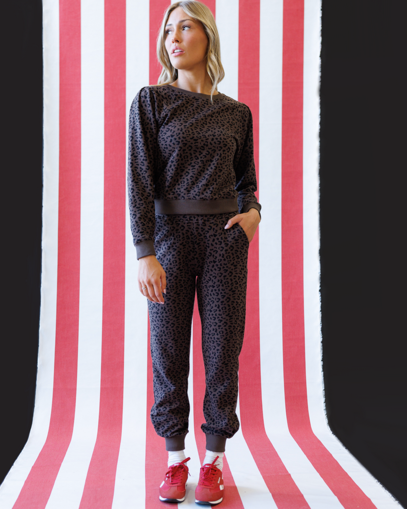 Woman wearing a black animal print outfit on a red and white striped background
