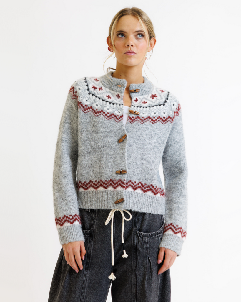 Woman wearing a gray sweater with red and white pattern on a white background