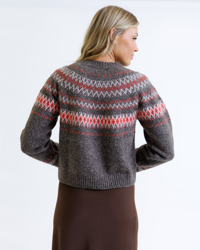 Woman wearing a multicolored geometric printed sweater with brown skirt on a white background