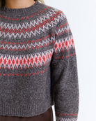 Woman wearing a multicolored geometric printed sweater on a white background