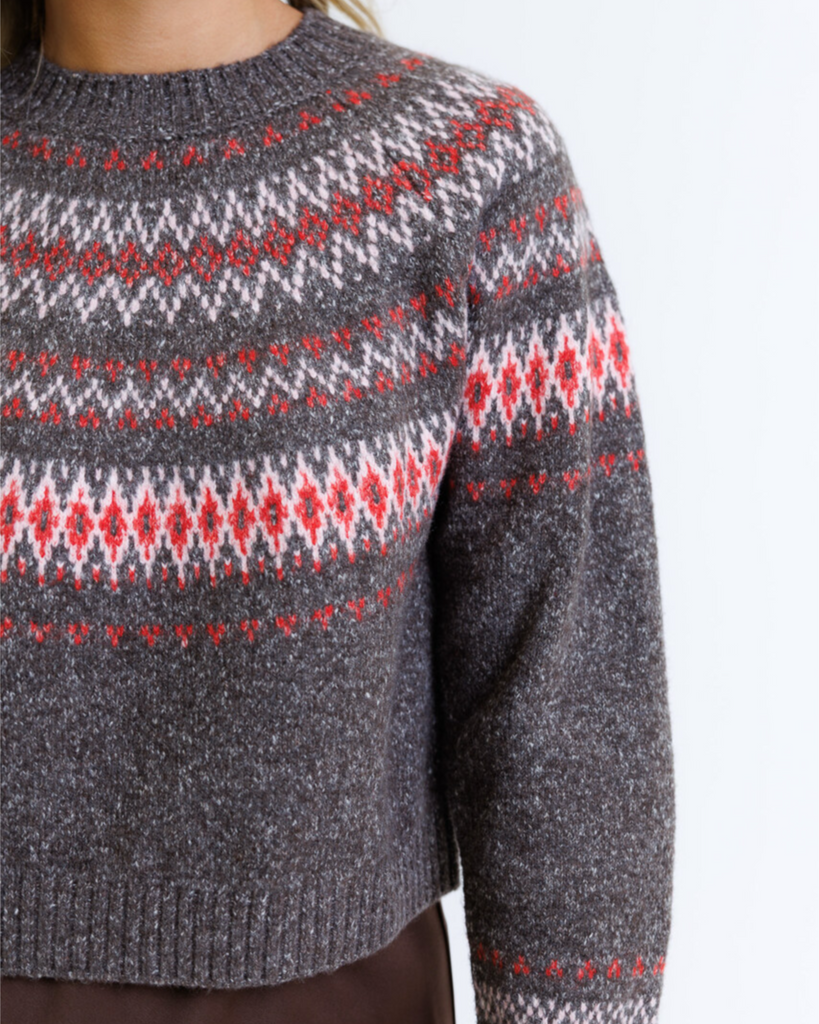 Woman wearing a multicolored geometric printed sweater on a white background