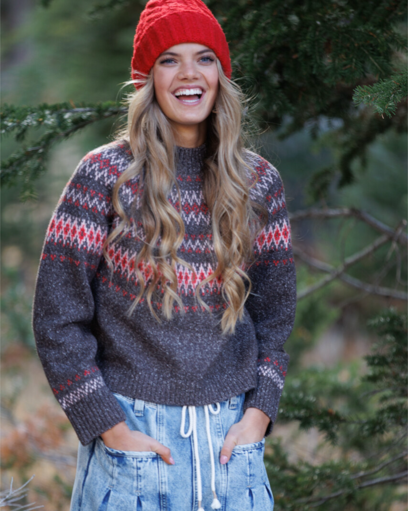 Woman wearing a multicolored geometric printed sweater and red beanie in the outdoors