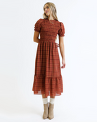Woman wearing a red and orange plaid dress on a white background
