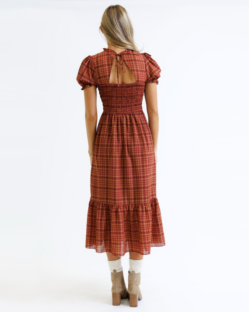 Woman wearing a red and orange plaid dress on a white background