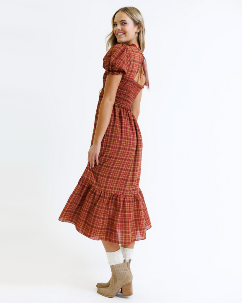 Woman wearing a red and orange plaid dress on a white background
