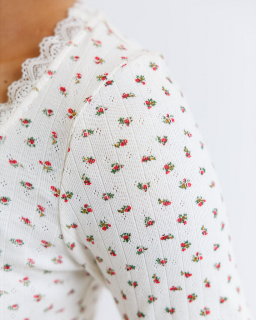 Woman wearing cream floral long sleeve with pointelle fabric on a white background