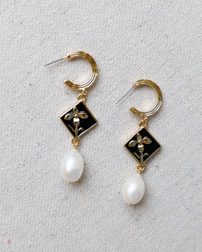 Gold hoop earrings with black square charms and pearl drops on a light gray background