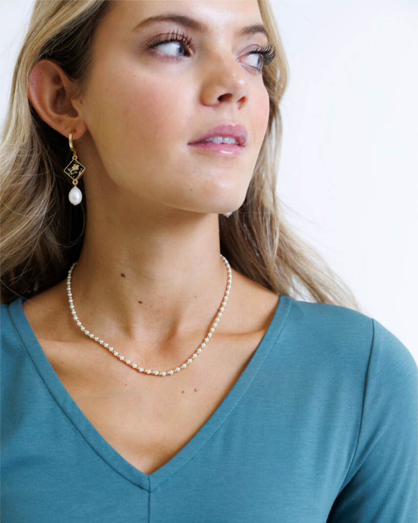 Woman wearing a pearl necklace and earrings on a plain background