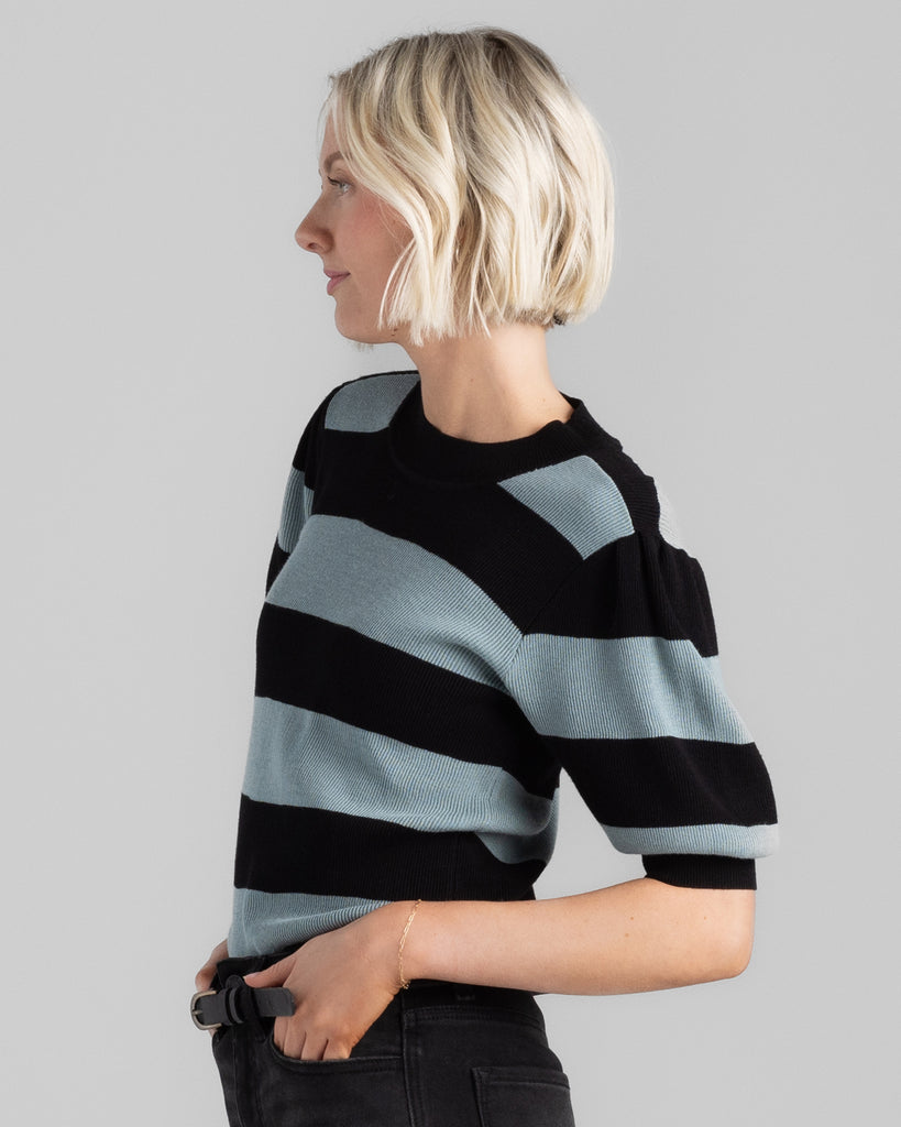 Model wearing a black and teal wide striped, short sleeve, crew neck sweater.