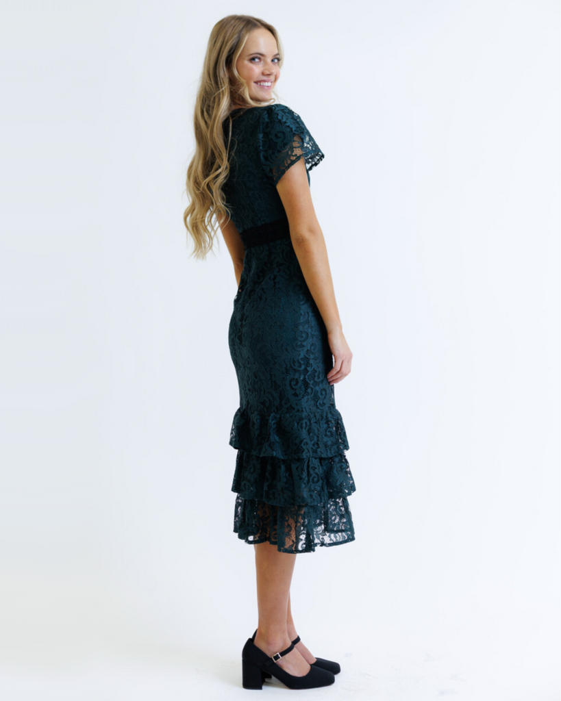Woman wearing a dark green lace dress on a white background