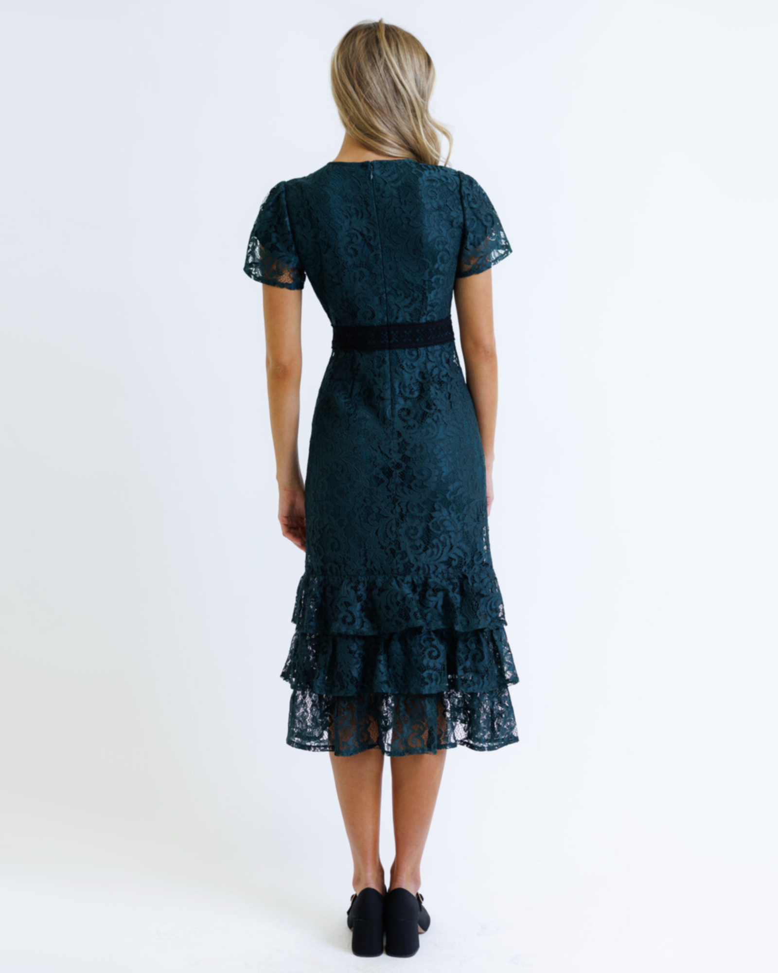 Woman wearing a dark green lace dress on a white background