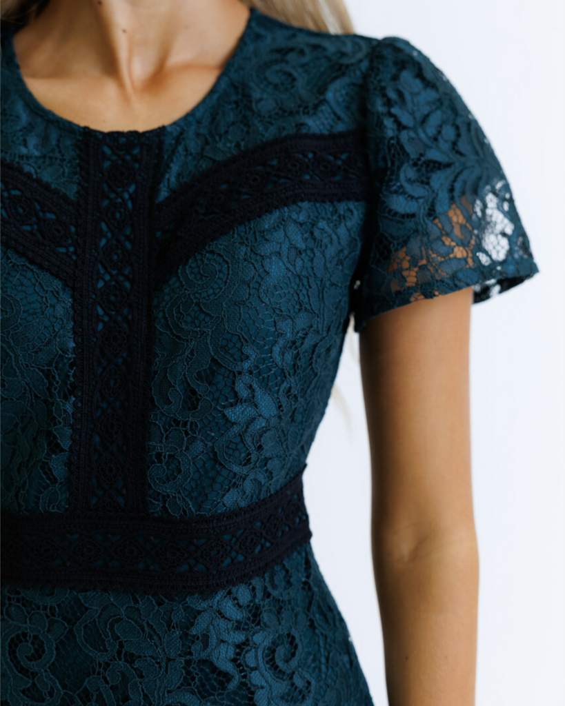 Teal lace dress with black accents on a white background
