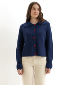 Woman wearing a blue knitted cardigan with red heart-shaped buttons on a white background