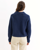 Person wearing a blue knitted cardigan with a collar on a white background
