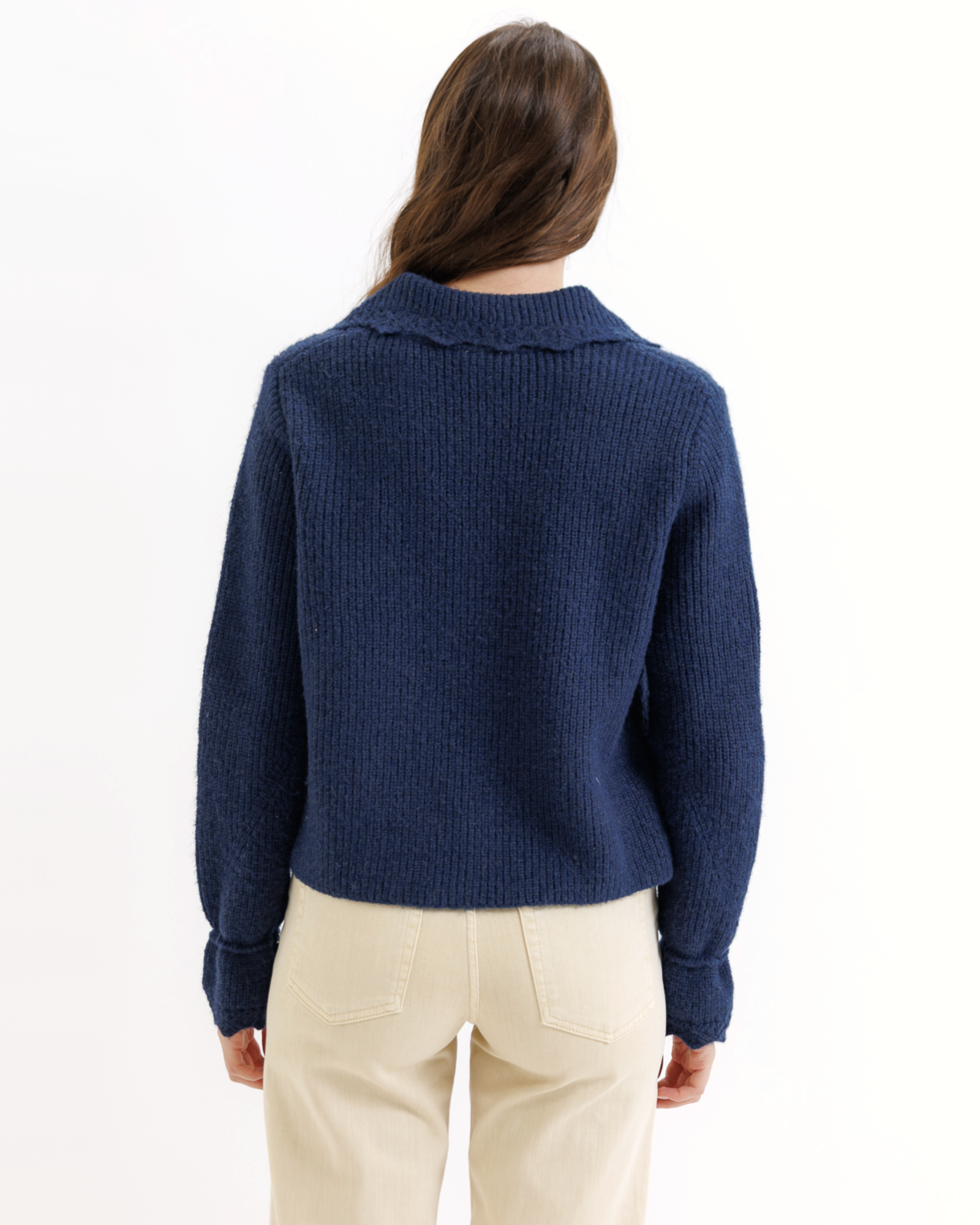 Person wearing a blue knitted cardigan with a collar on a white background