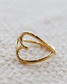 Gold heart-shaped ring on a textured beige surface