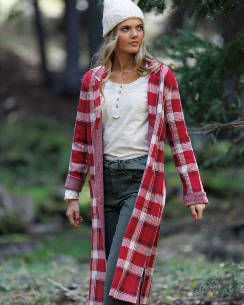 Woman wearing a red plaid coat and cream colored shirt in the outdoors