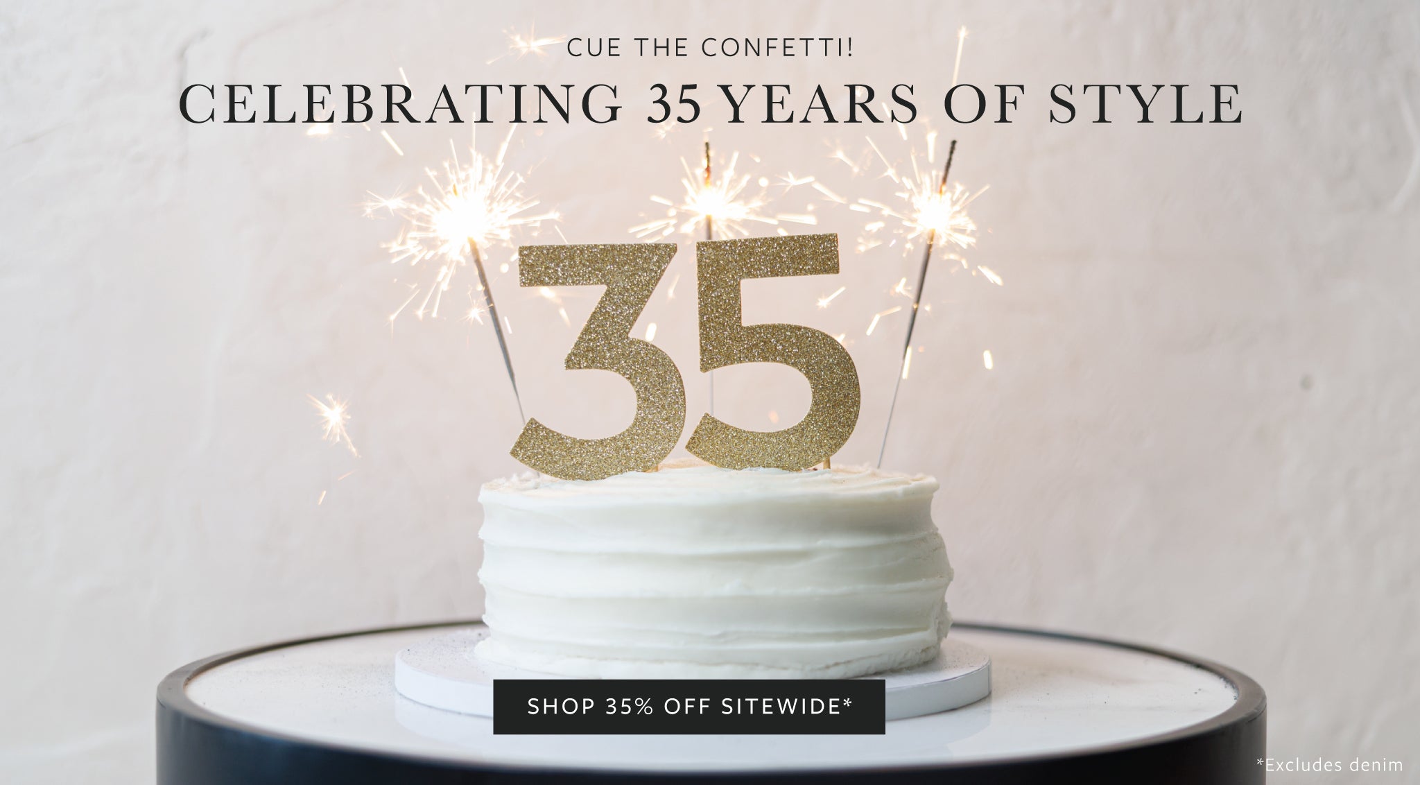A white frosted cake on a round table with gold glitter number 35 candles and sparklers, under the text 'CELEBRATING 35 YEARS OF STYLE'.