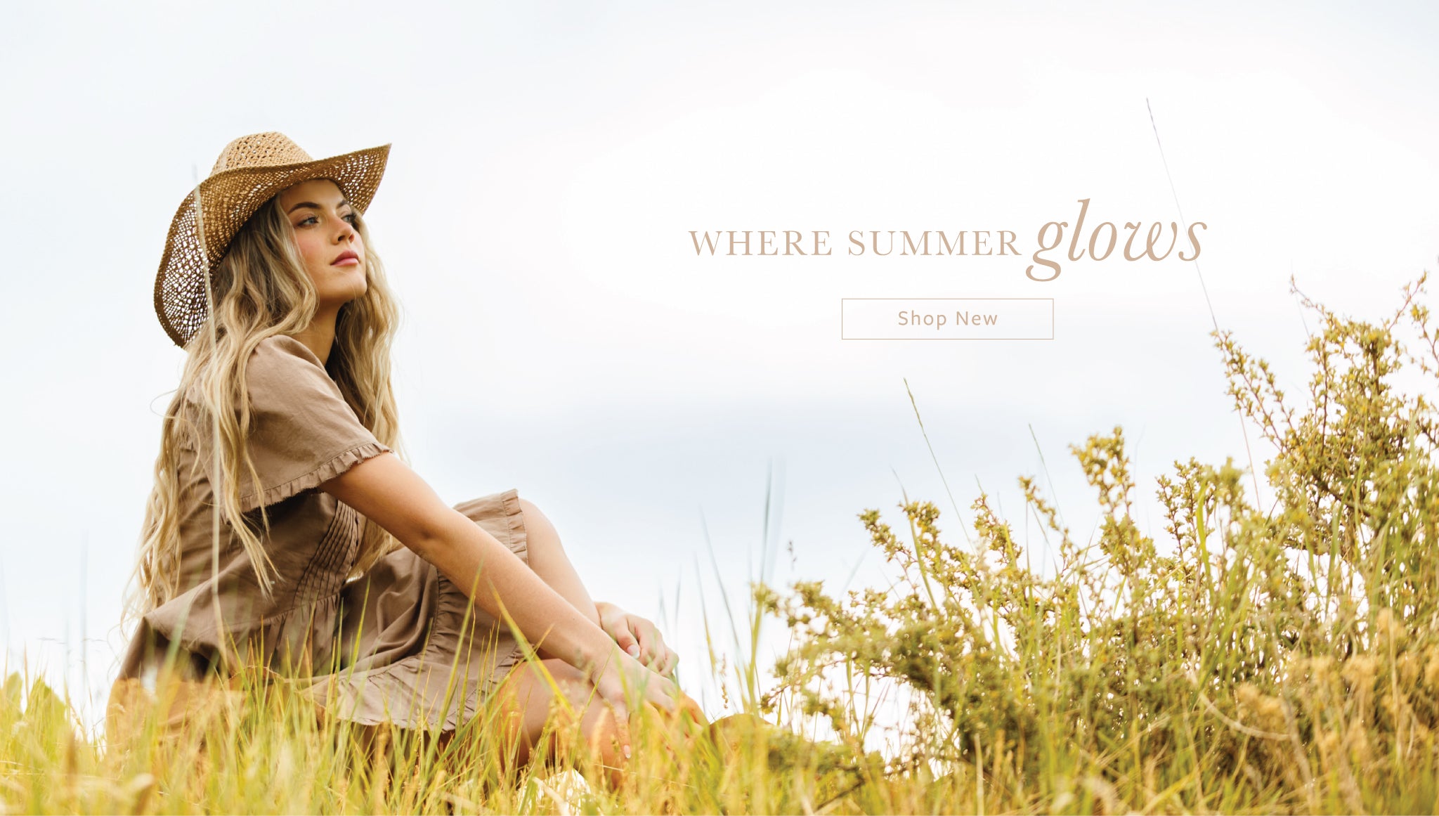 A woman wearing a straw hat and a beige dress sits in a grassy field under a bright sky, with the text 'WHERE SUMMER glows' and a 'Shop Now' button on the right side.