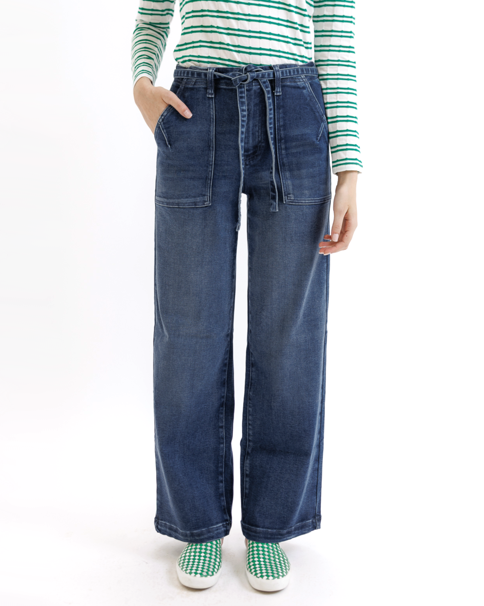 Woman wearing a green and white striped shirt and blue jeans on a white background
