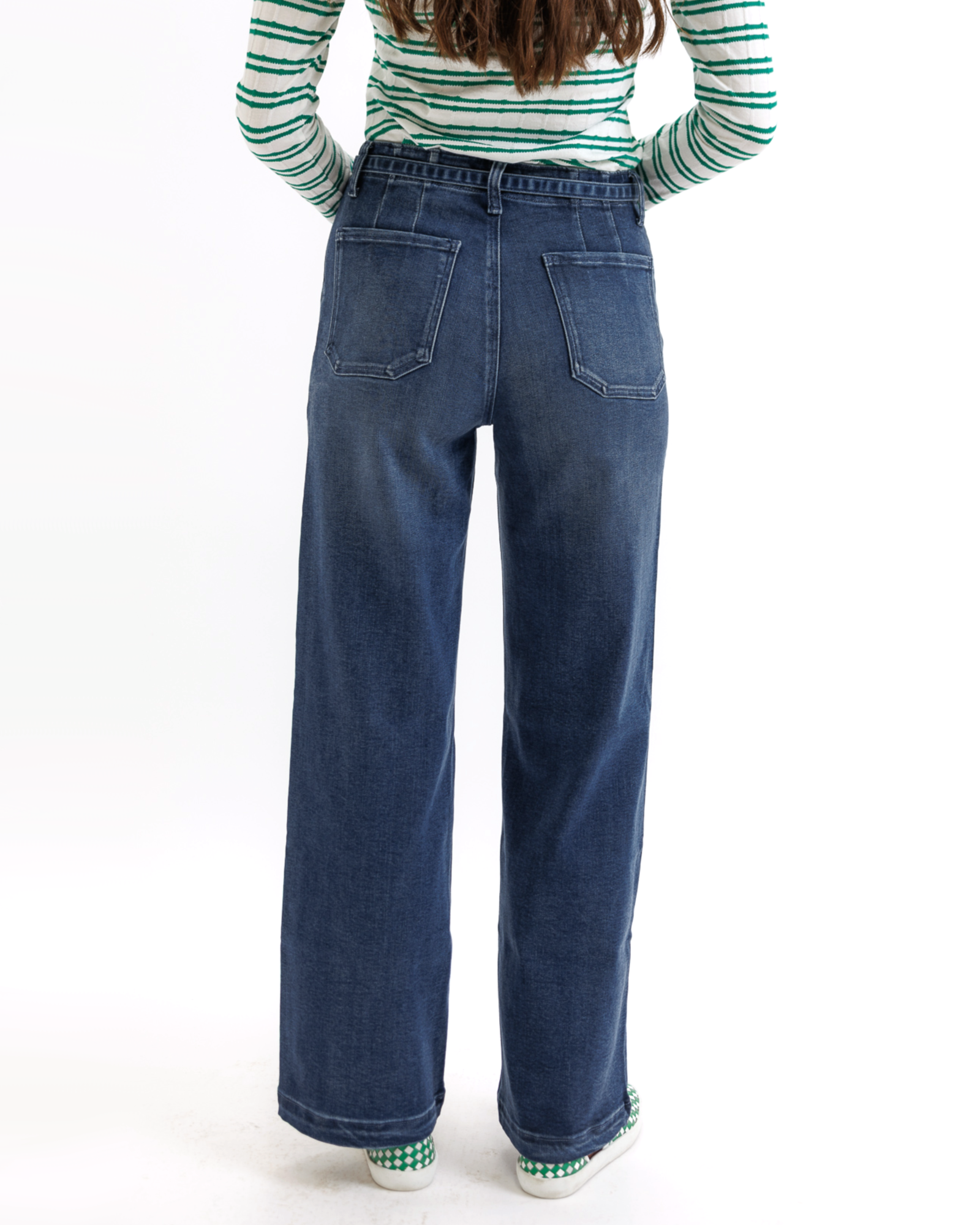 Woman wearing a green and white striped shirt and blue jeans on a white background